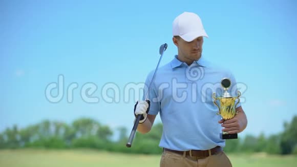 自信的高尔夫球手带金杯和球杆相机微笑运动冠军视频的预览图