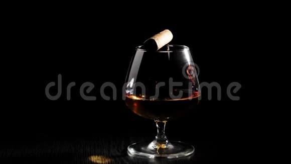 豪华白兰地玻璃上的雪茄与金色干邑旋转在黑色桌子上的黑色背景白兰地白兰地嗅探器视频的预览图