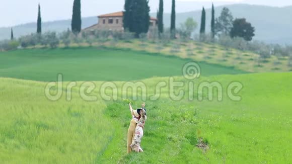 两个年轻的女人带着帕纳马斯拥抱在绿色的田野上摆姿势挥动双手为无人机射击视频的预览图