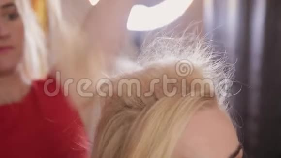 一个年轻的女人坐在理发师扶手椅上理发师做发型一个年轻的金发女人来到视频的预览图