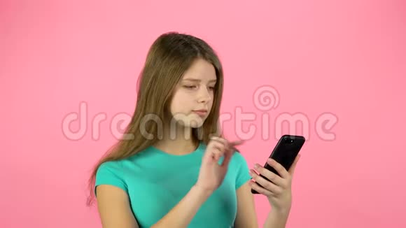 女孩在视频聊天在演播室的手机与粉红色背景视频的预览图