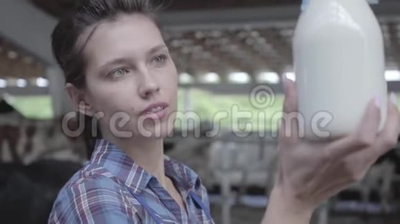 奶牛场年轻女职工画像检查奶瓶特写中牛奶质量积极的农民视频的预览图