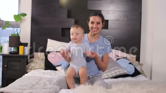 一位年轻的母亲和她一岁的小儿子在家里床上跳视频的预览图