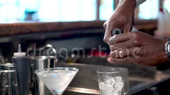 酒吧男将酒精倒入一杯加冰的杯子中加入世界大都会鸡尾酒视频的预览图