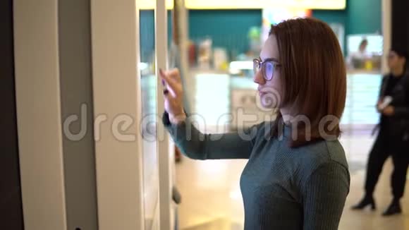 一位年轻女子在购物中心的触摸终端点菜现代技术在食品法庭上视频的预览图