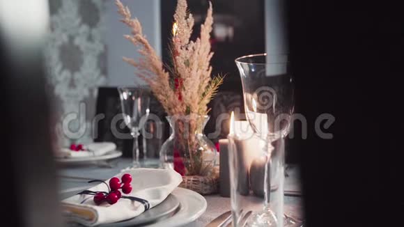 圣诞餐桌装饰一支燃着的蜡烛带眼镜的宴会桌一张圣诞餐桌的特写视频的预览图