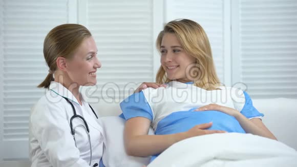 微笑的产科医生和抱着肚子看镜头的孕妇视频的预览图