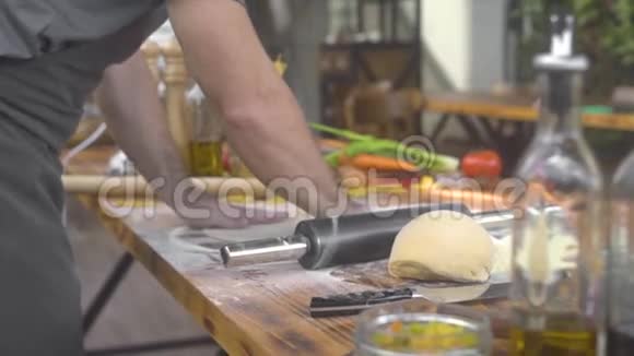 厨师用滚轴把面粉洒在披萨面团上为意大利面食做面团的人视频的预览图