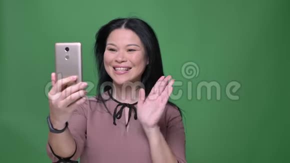 一位年轻迷人的黑发亚洲女性的特写镜头她在手机上打了一个视频电话背景是孤立的视频的预览图