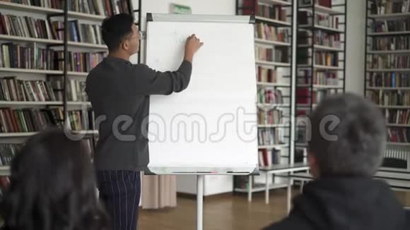 一位年轻的亚裔男子在演讲中站着一张挂图视频的预览图