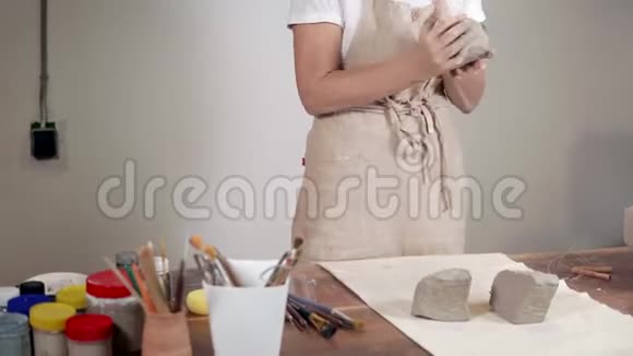 女雕塑家在车间用灰色粘土做圆坯视频的预览图
