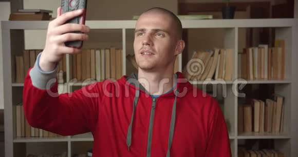在大学图书馆里一位年轻迷人的白种人男学生在电话中视频通话的特写镜头视频的预览图