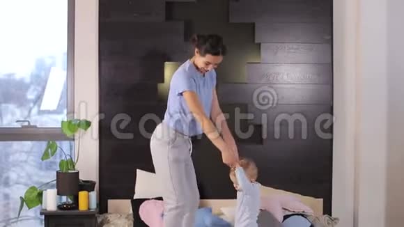 一位年轻的母亲和她一岁的小儿子在家里床上跳视频的预览图