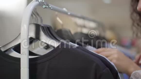 女人正在服装店的货架上寻找t恤她的手在特写视频的预览图