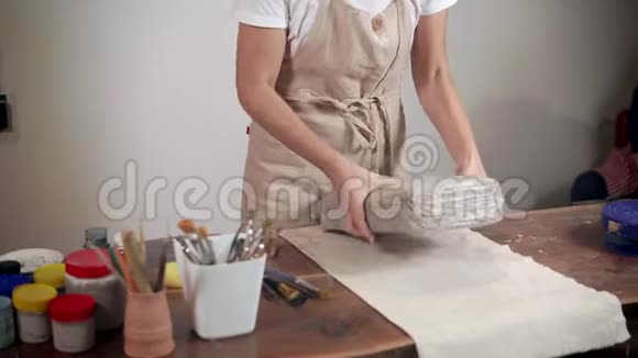女雕刻家在车间用灰色粘土切割包装视频的预览图