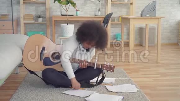 一位非洲裔美国妇女她留着非洲发型坐在地板上拿着吉他经历了一场创造性的危机视频的预览图