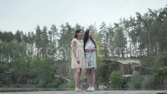 两个美丽的女人站着说话微笑女孩们看着神奇的大自然壮观的景色视频的预览图