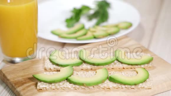 女厨师把鳄梨切片放在全麦黑麦面包上为健康早餐或小吃做鳄梨吐司视频的预览图