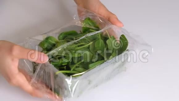 女人在白色的桌子上用食物片做菠菜包装产品用透明聚乙烯食品膜辊视频的预览图