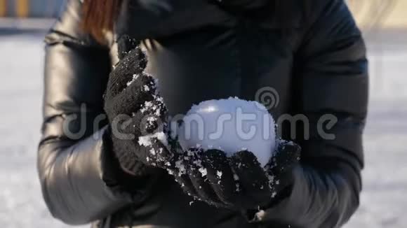 一个戴手套的女孩拿着雪球手拿雪在晴朗的冬天玩雪球冬季概念视频的预览图