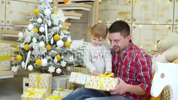 小女孩带着爸爸在家附近的圣诞树上打开礼物盒视频的预览图