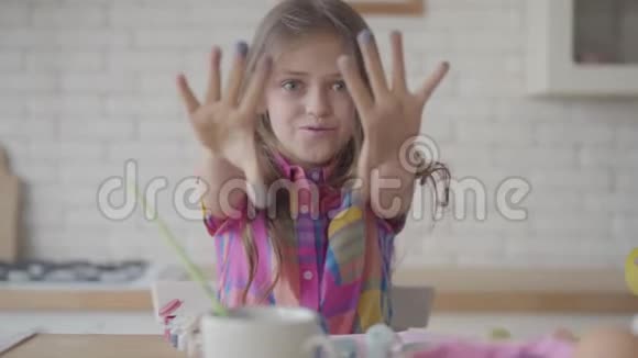 可爱的情绪激动的小女孩留着长发用蓝色的颜料在厨房里做了一个鬼脸视频的预览图
