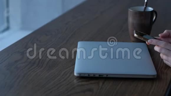 女性手拿着智能手机在咖啡店背景是笔记本电脑视频的预览图