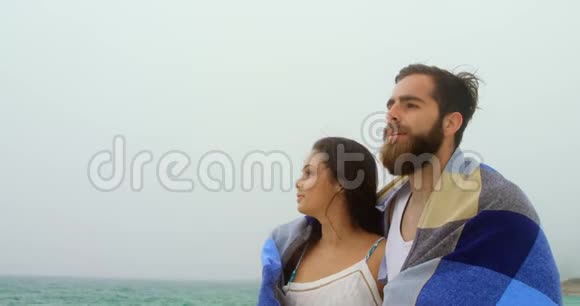 高加索夫妇在海滩上用毯子散步的正面景色视频的预览图
