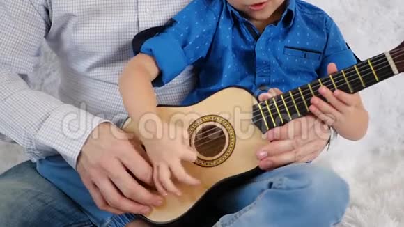爸爸教儿子坐在蜂巢沙发上弹吉他视频的预览图