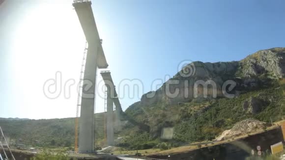 从旅游巴士的窗口观看黑山在峡谷之间建造一座现代化的高桥慢动作视频的预览图