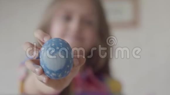 可爱的小女孩手里拿着蓝色复活节彩蛋手里拿着画好的心把它拿给相机看焦点从视频的预览图