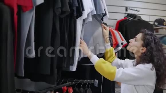 十几岁的女孩正独自在时装店检查t恤衫视频的预览图