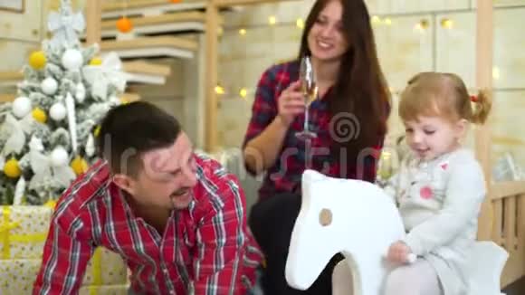 小女孩在父母旁边摇着马摆庆祝圣诞节视频的预览图