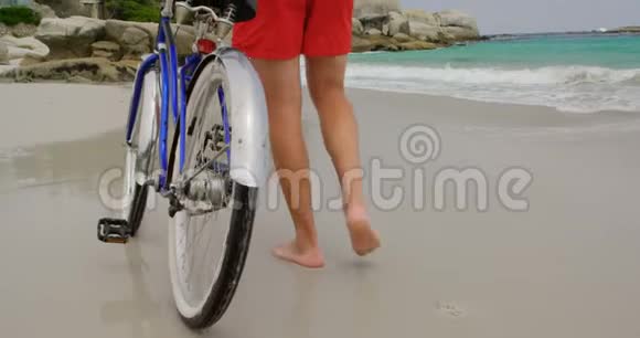 高加索人在海滩上骑自行车行走的后景视频的预览图