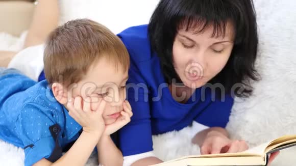 快乐的母亲在白色沙发上给孩子读一本书视频的预览图