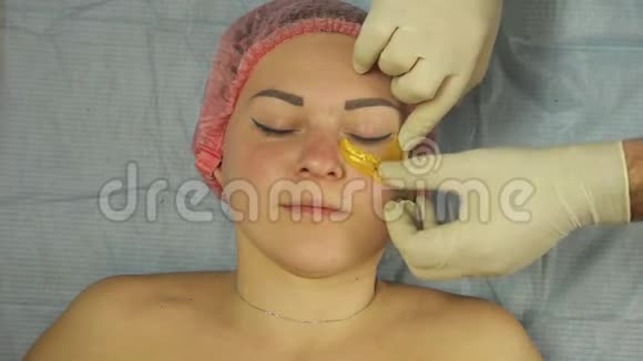 一位戴手套的男性美容师将胶原蛋白垫放在女人下眼皮上视频的预览图