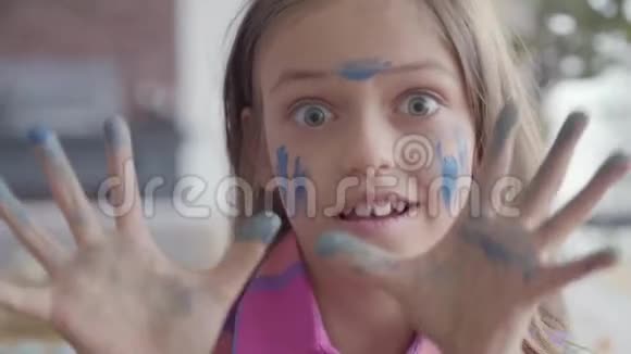 特写真实有趣的小女孩的肖像可爱的情感小女孩用蓝色的水彩画脸视频的预览图