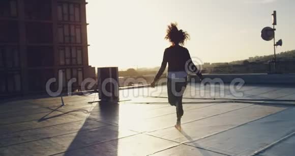 城市屋顶上的时尚年轻女性双臂伸展视频的预览图