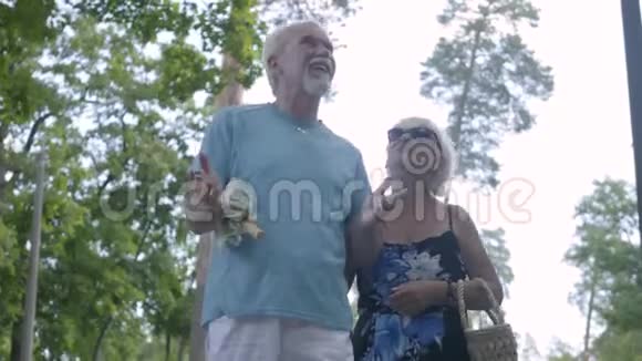 一对幸福成熟的夫妇一起在公园散步的正面景色老妇人拿着袋子男人拿着一个视频的预览图