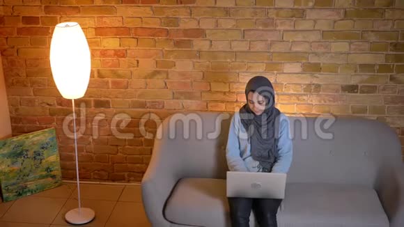 年轻活泼的穆斯林少女戴头巾在笔记本电脑上发短信同时还要打视频电话视频的预览图