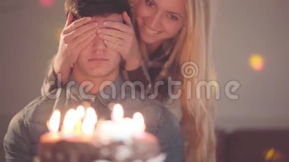 金发女孩遮住了男人的眼睛然后让他看到了有许多蜡烛的蛋糕他要庆祝生日视频的预览图