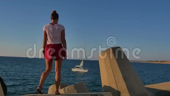 穿短裤的漂亮女孩在海边的大石头上跳舞视频的预览图