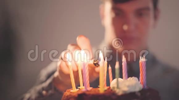 英俊的年轻人坐在小蛋糕前面用打火机点燃蜡烛孤独的人有生日聚会视频的预览图