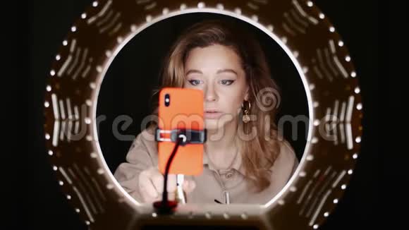 女性时尚博主用手机在灯光前勾勒脸型视频的预览图