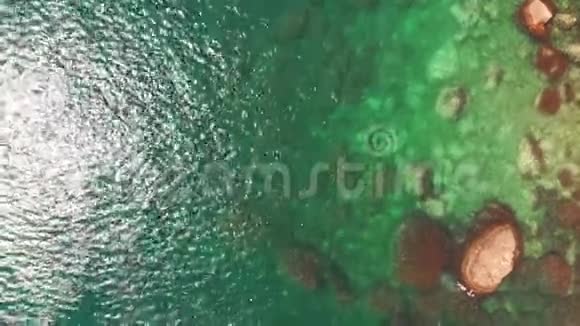 空中无人驾驶飞机鸟眼镜头拍摄的女子在海洋水面的石头中游泳晶莹剔透视频的预览图