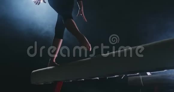职业女体操运动员在平衡木上的烟雾中缓慢地跳跃女子艺术体操视频的预览图