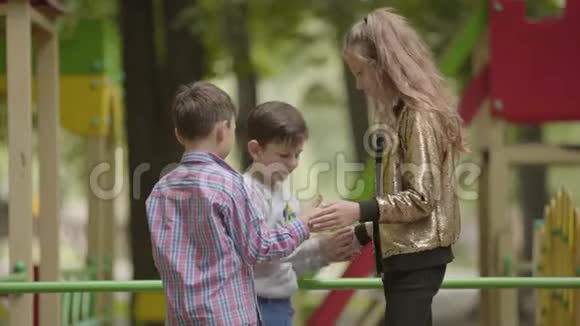 三个可爱的孩子一起在户外玩耍孩子们在操场上无忧无虑的童年视频的预览图