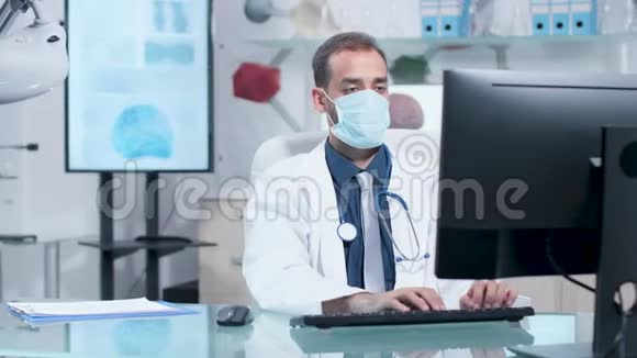 年轻医生戴着面具在电脑上打字视频的预览图
