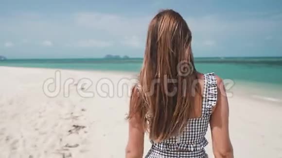 在阳光明媚的日子里女人在沙滩上散步视频的预览图