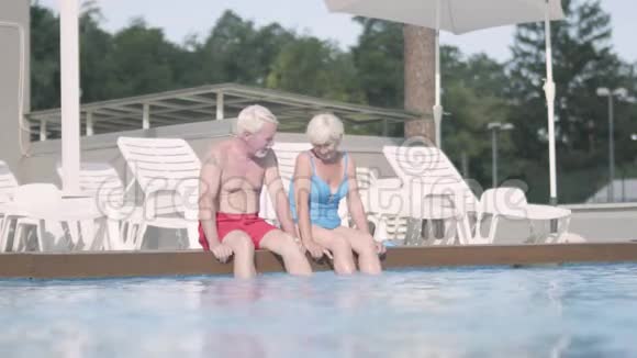 幸福成熟的夫妻坐在池边可爱的高级男女在酒店综合体放松拥抱视频的预览图